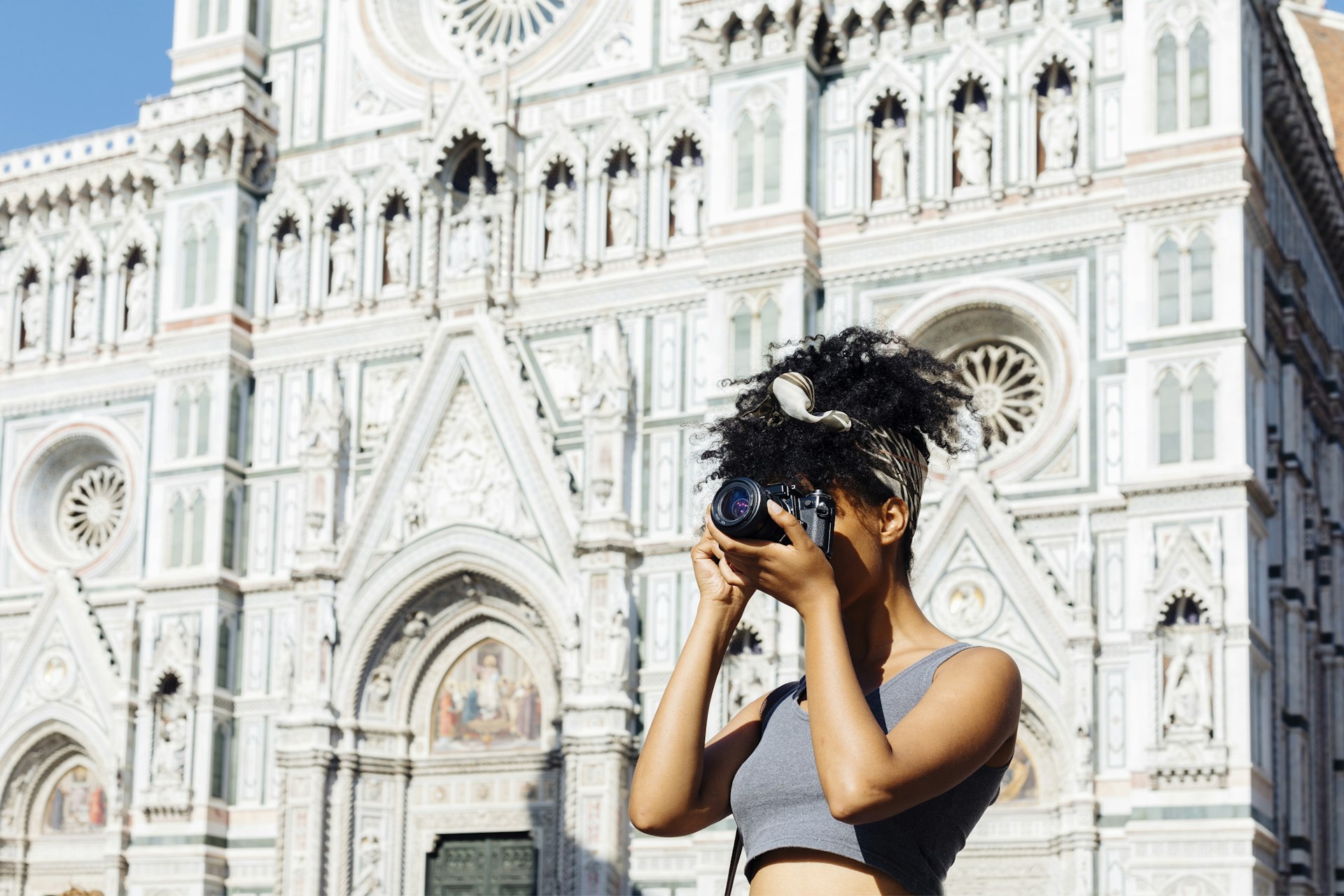 Young woman taking photo with camera in front of cathedral, Florence, Italy